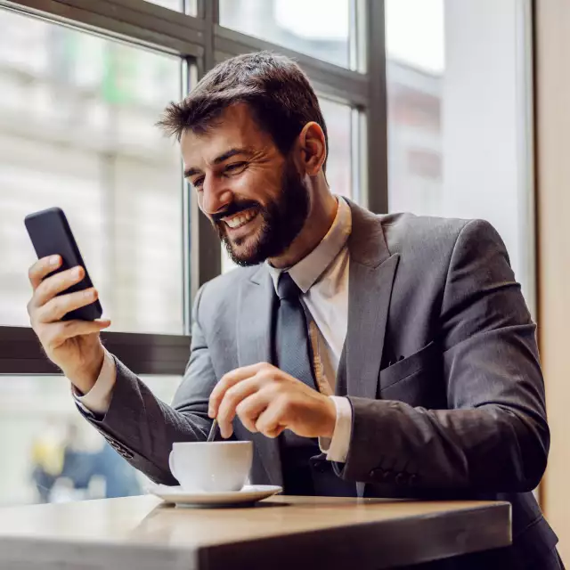 Man drinking coffee and looking at cell phone