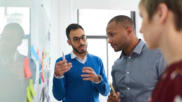 Coworkers using sticky notes on wall