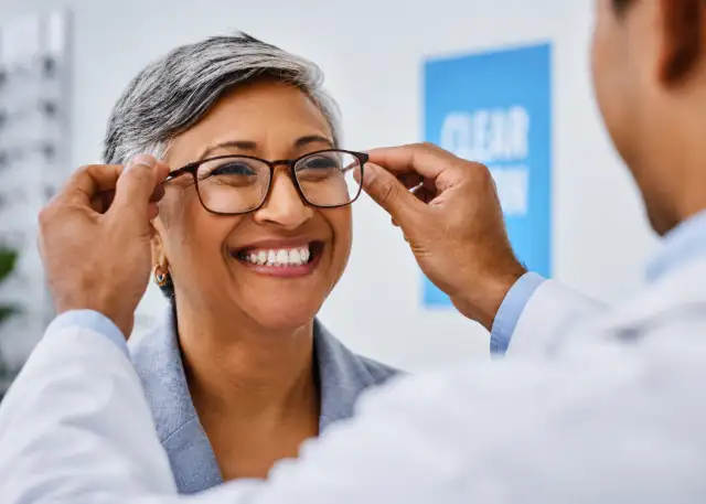 Doctor putting eyeglasses on patient