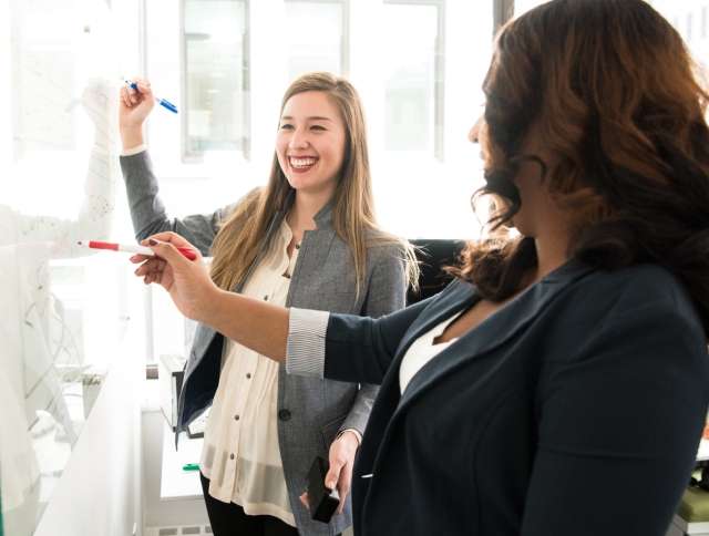 Two woman working together on a whiteboard