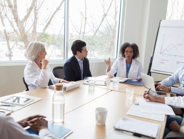 Scientists in lab coats holding a forecasting meeting