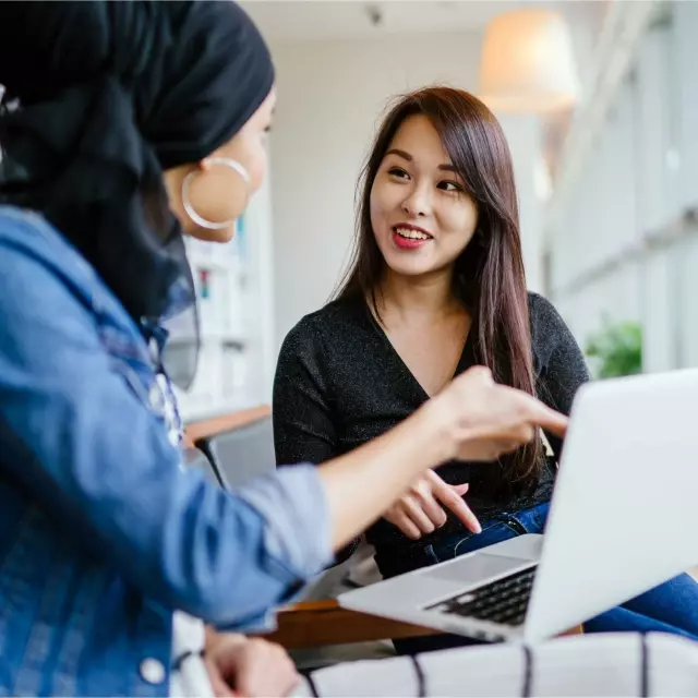 Women discussing benefits of Conga CLM while working on laptop