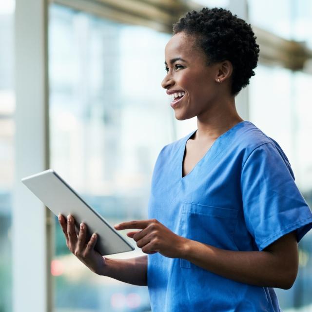 Nurse smiling and holding a tablet